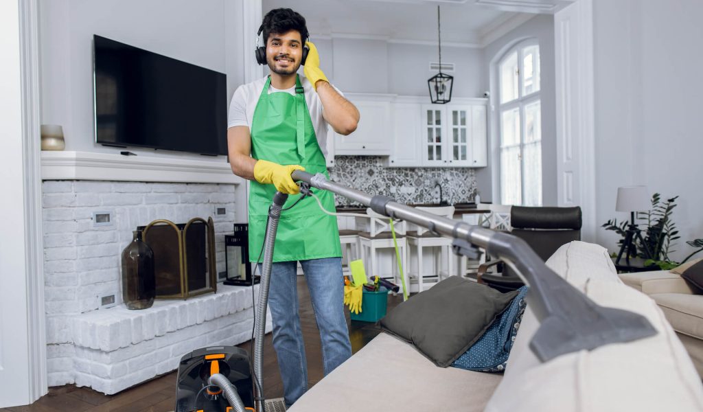 smiling-man-cleaning-sofa-and-listening-music-2021-12-09-06-25-39-utc.jpg